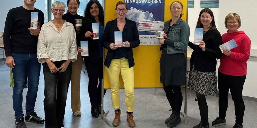 Die Gruppe der Bildungsberatung Salzburg steht vor einem Plakat