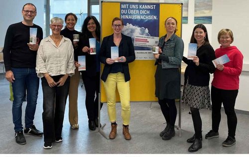 Die Gruppe der Bildungsberatung Salzburg steht vor einem Plakat
