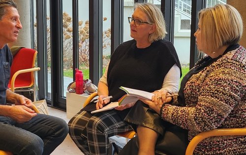 3 Teilnehmer:innen sitzen im Kreis und diskutieren.